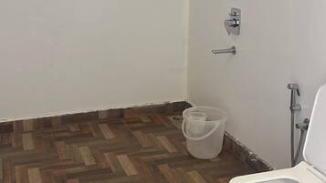 Ein Badezimmer mit Holzboden, Toilette, Dusche und einer Wandleuchte.