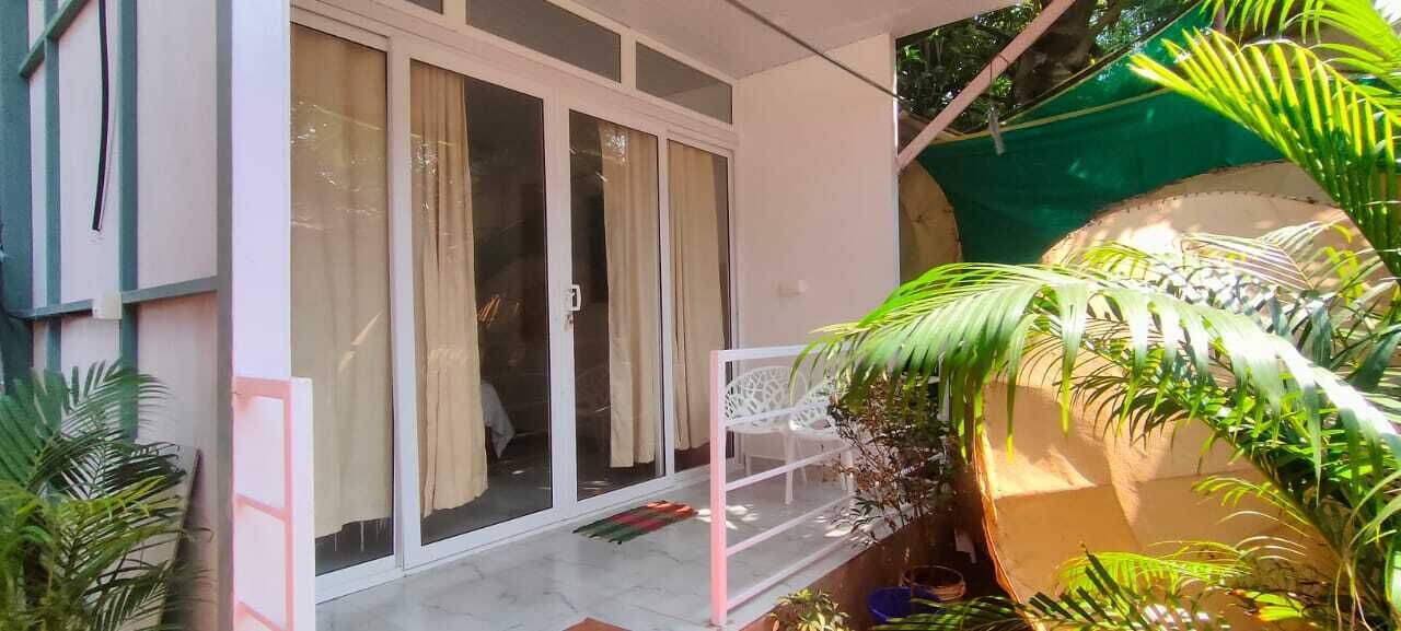 A house with a sliding glass door, a white chair, and various plants.