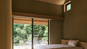 A bedroom with a large sliding glass door leading to an outdoor deck, wooden flooring, and a bed with white bedding. - GEOSPOT MOTOHAKONE B (Hakone)