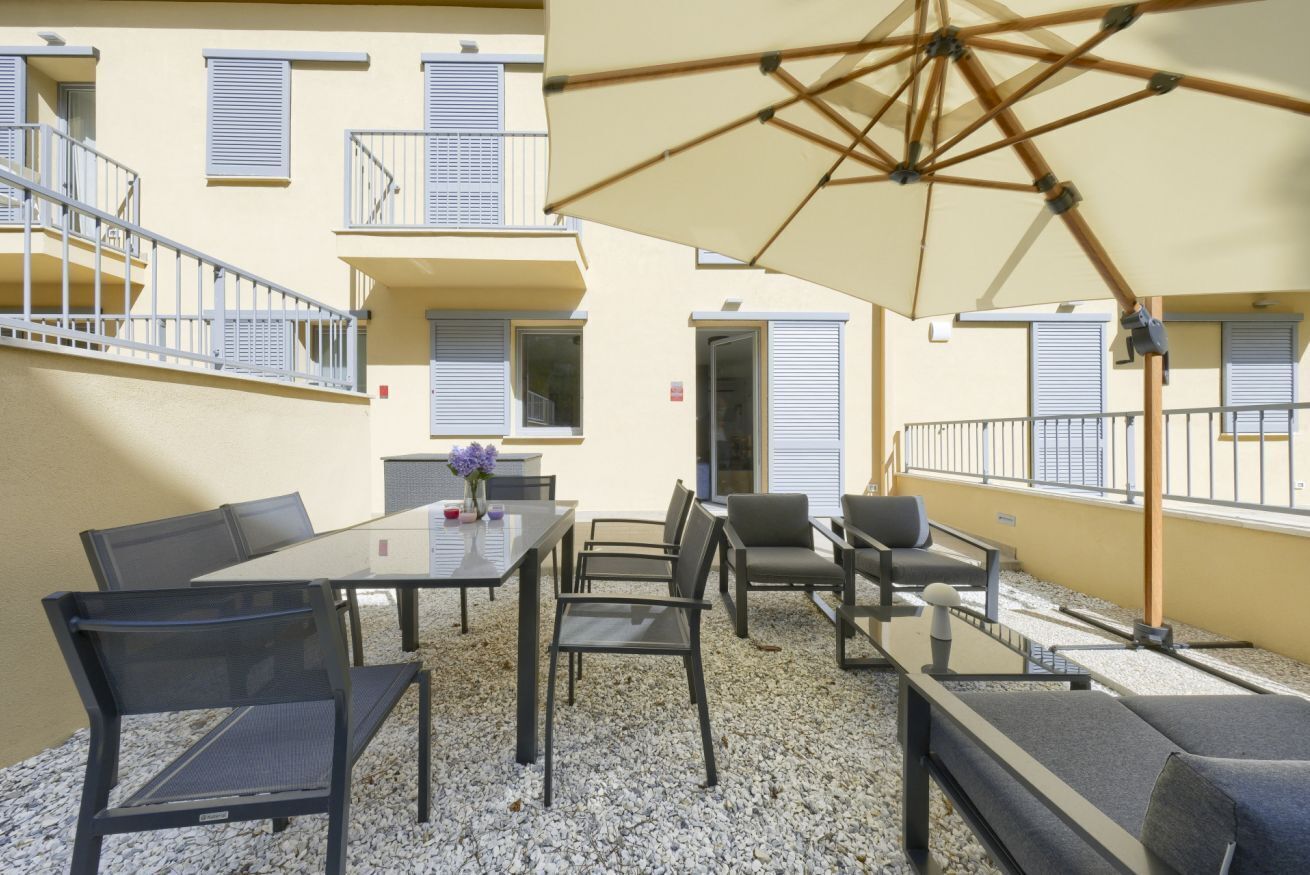 An outdoor seating area with a table, chairs, and an umbrella.
