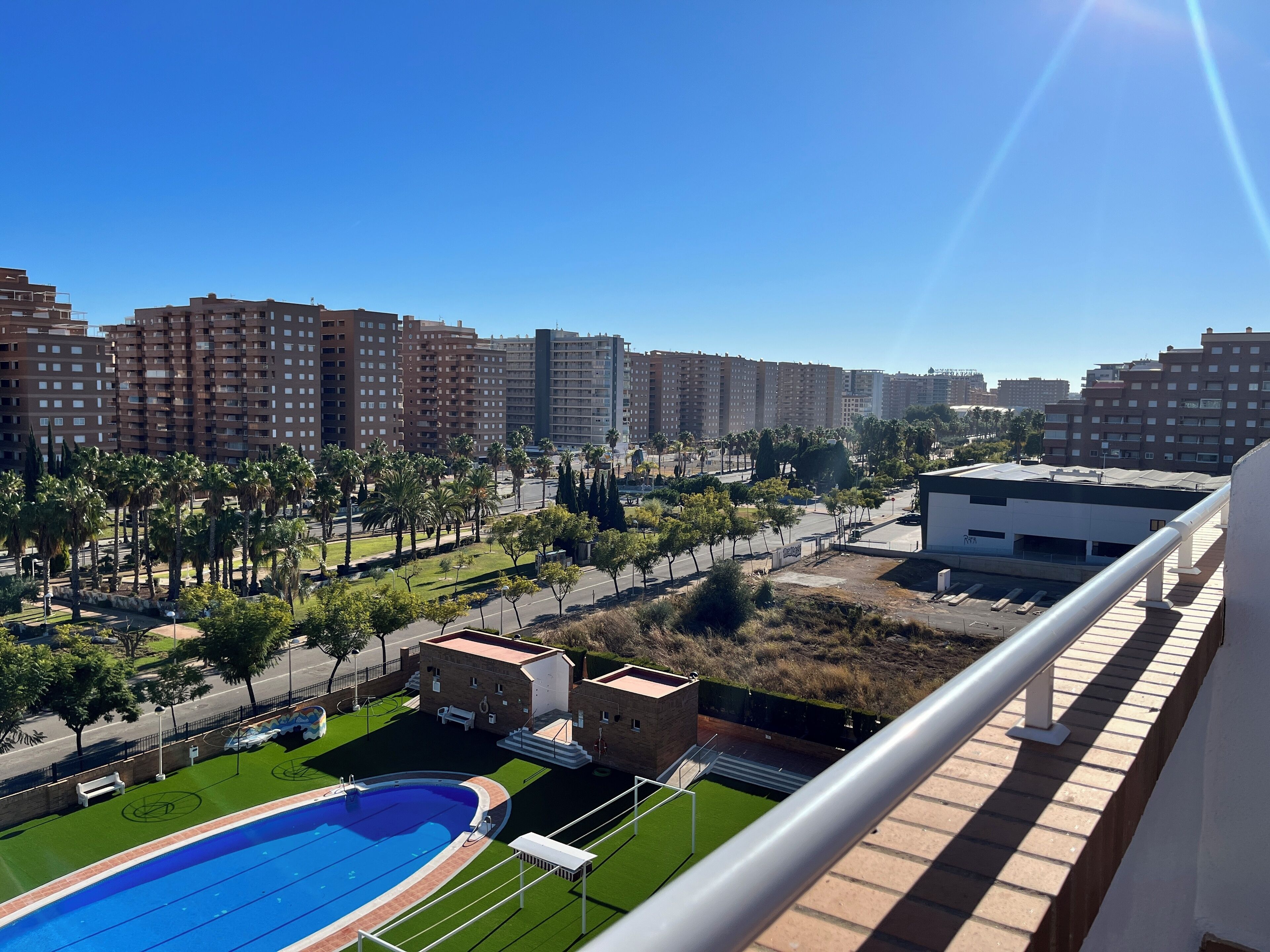 A residential area with a swimming pool, a basketball court, and a view of high-rise buildings.
