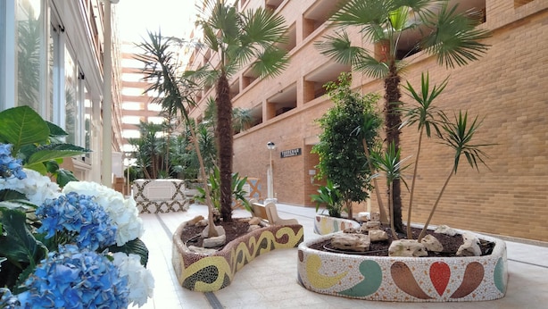 A courtyard with potted plants, a tiled floor, and a building with a brick facade. - ACV - Apartamentos Torremar (Oropesa del Mar)