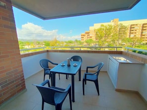 Een balkon met een tafel en stoelen, en een uitzicht op gebouwen en groen.