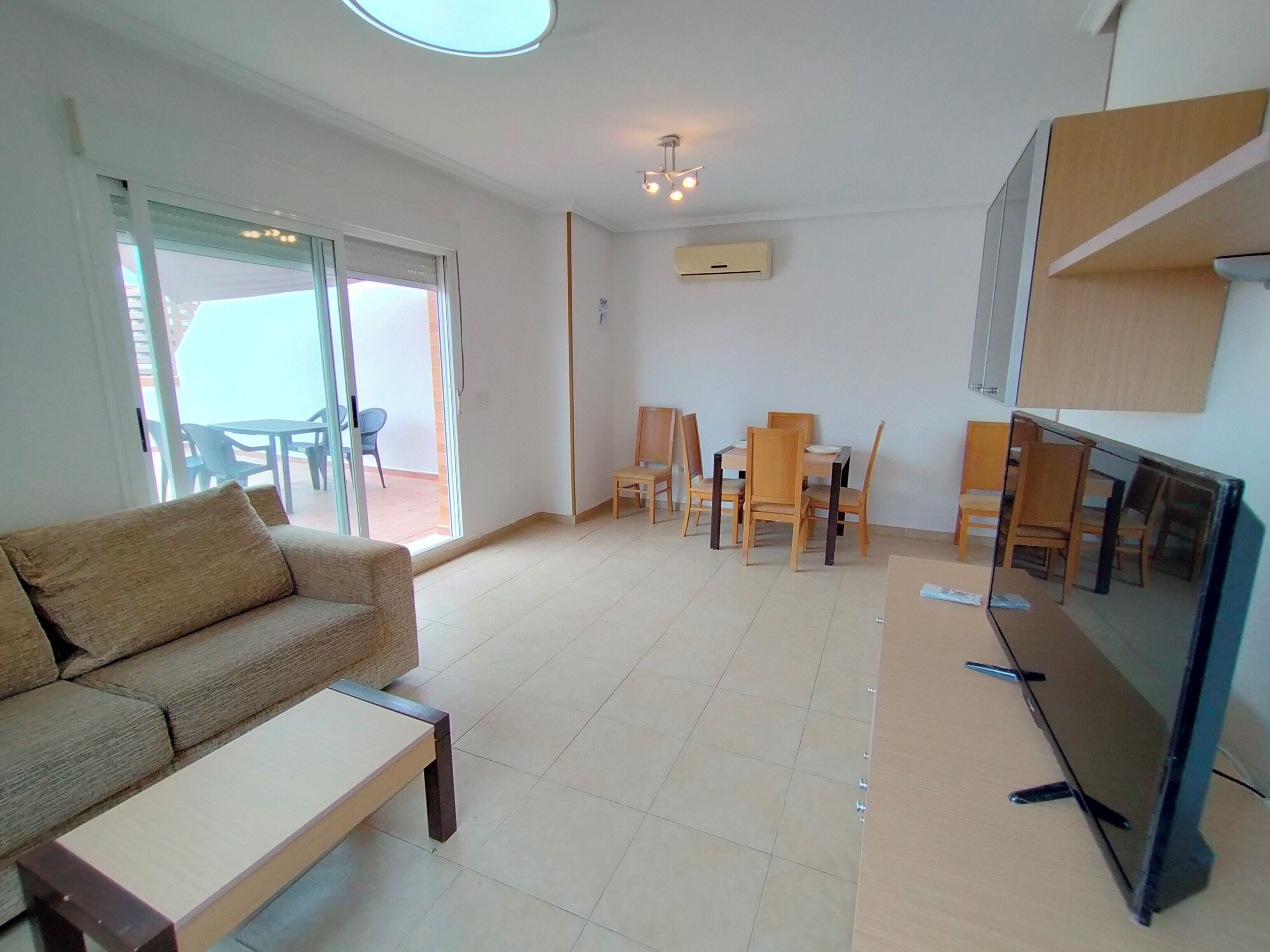 Un salon comprenant un canapé, une table basse, un téléviseur et un coin repas avec des chaises et une table.