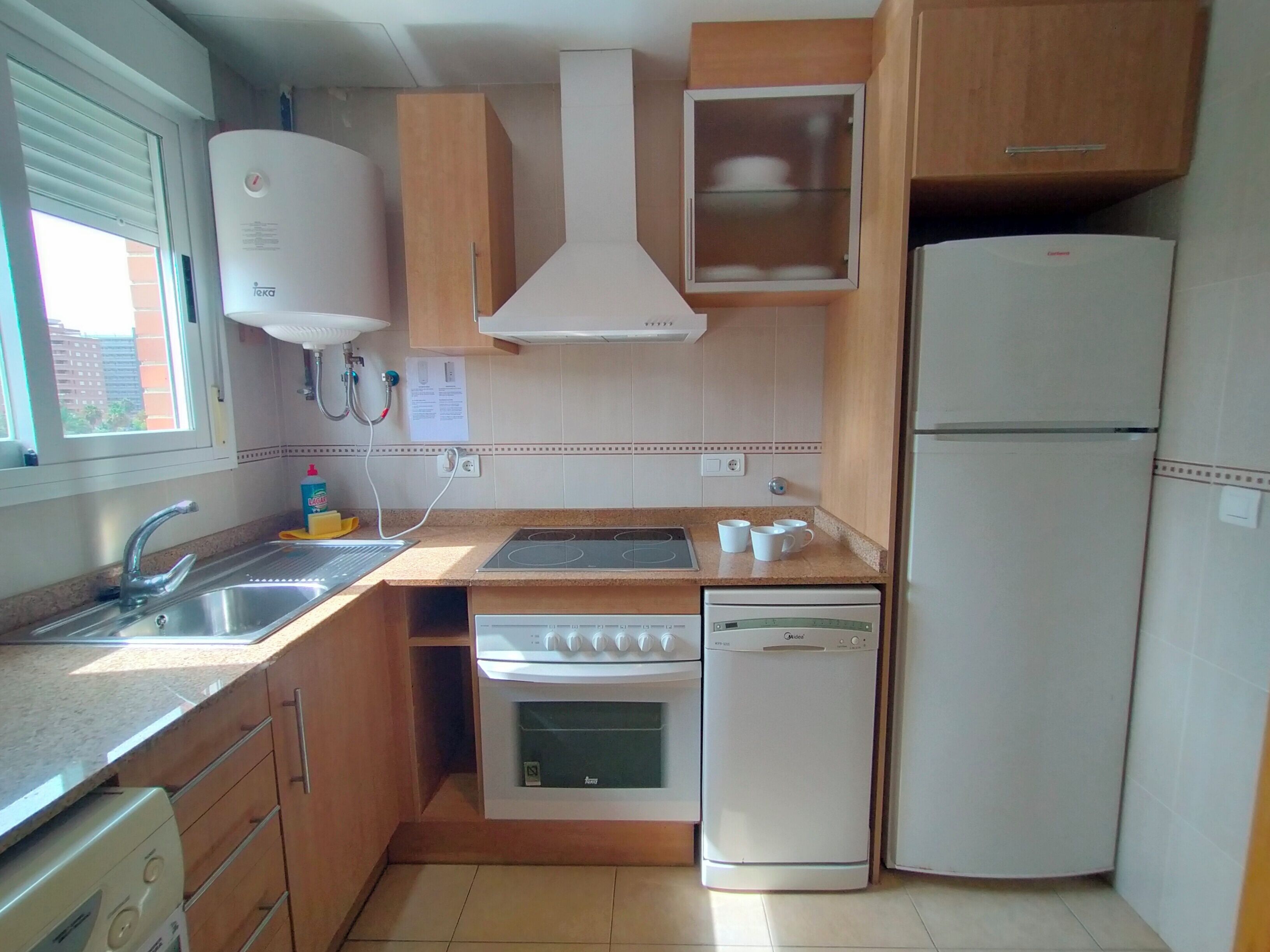 Eine kleine Küche mit Spüle, Herd, Backofen und Kühlschrank.