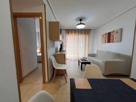 Un espacio habitable compacto con kitchenette, comedor, sofá y ventilador de techo.