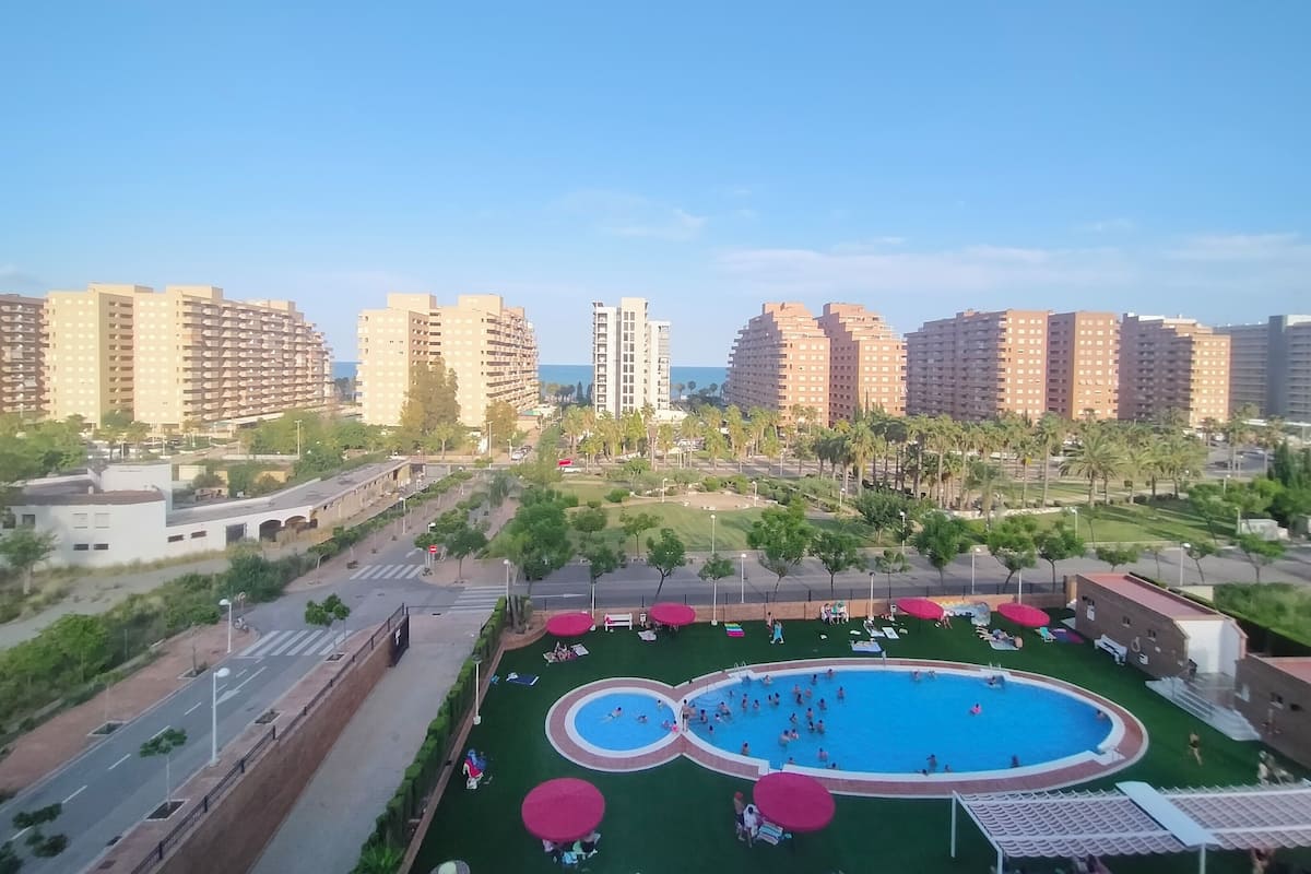 Een woonwijk met hoge flats, een zwembad en een park met parasols.