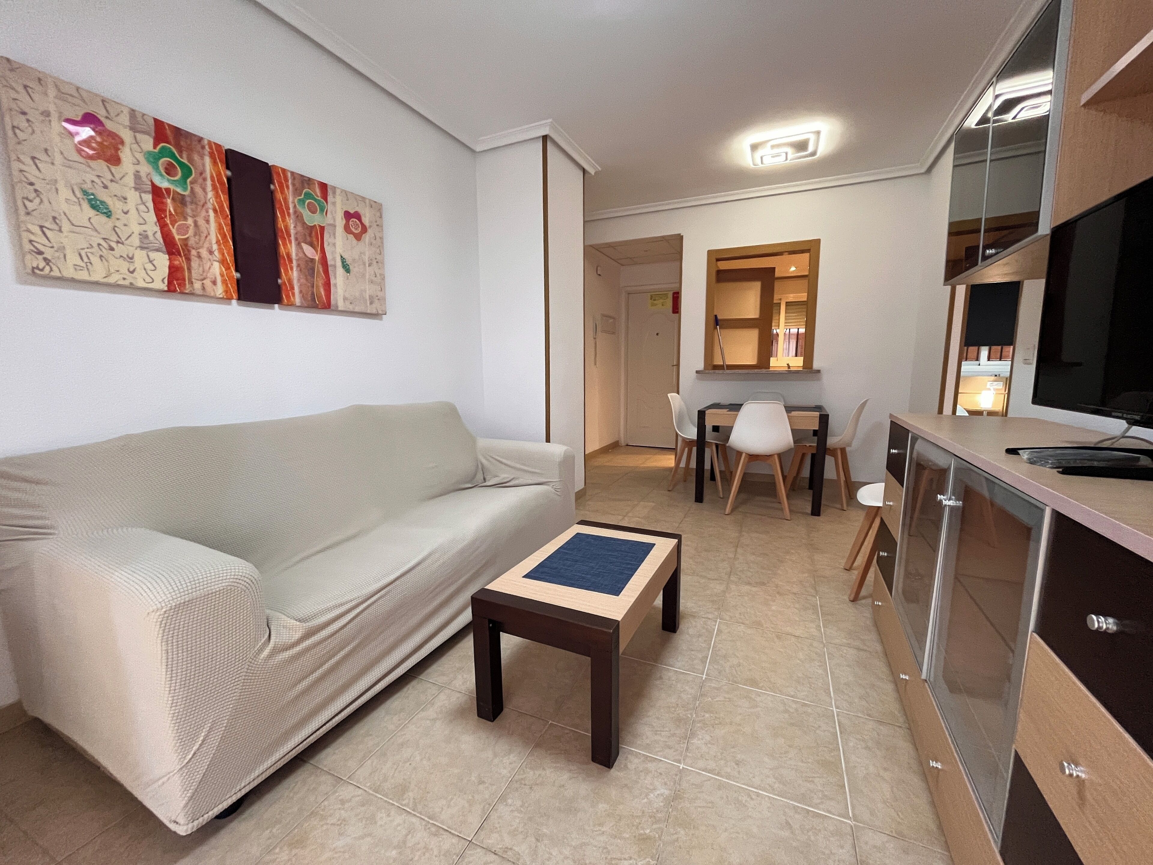 A living room with a sofa, a coffee table, and a dining area with chairs and a table.