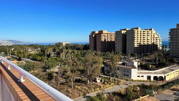 Un paisaje urbano costero con rascacielos, cielo azul despejado y vista al mar.