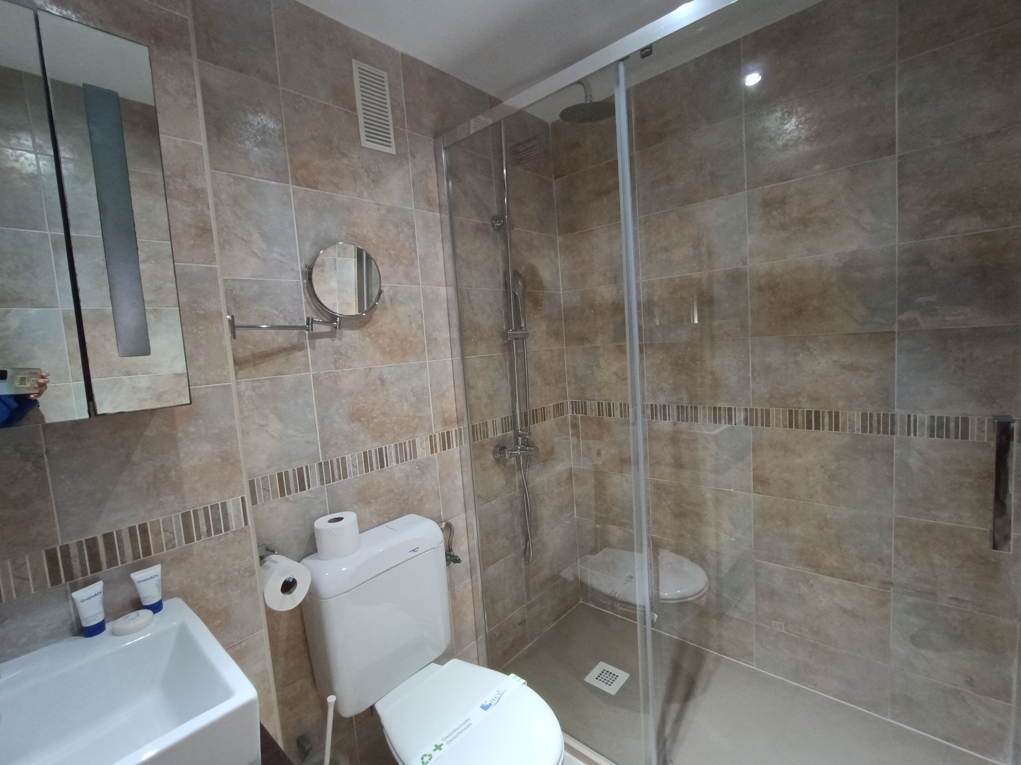 A bathroom with a toilet, sink, and shower area.