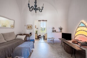 Ein gemütliches Zimmer mit einem Bett, einem Schreibtisch mit Fernseher, einer Kristallleuchtre und einem großen Fenster.