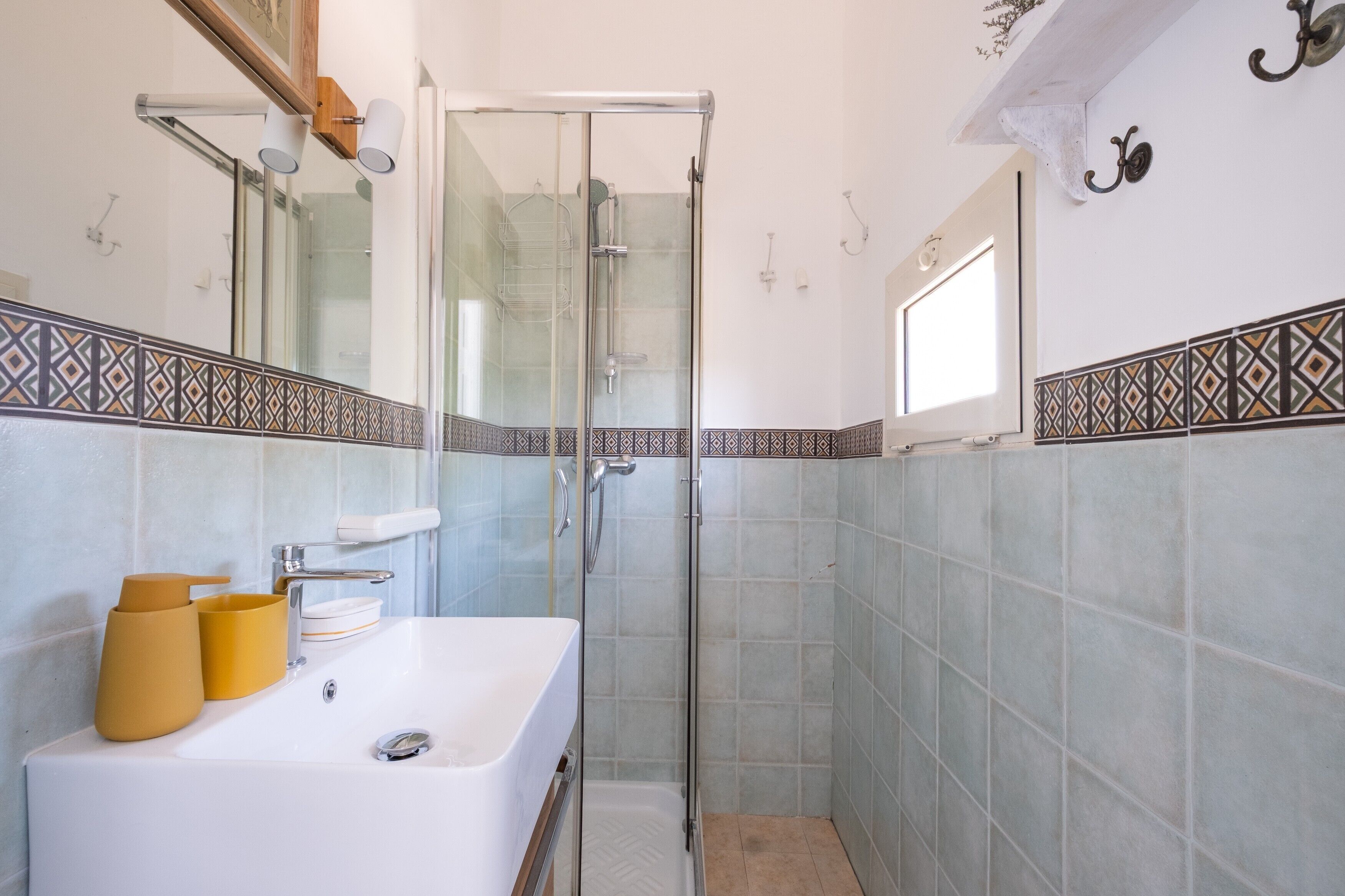 Une salle de bain avec une douche à parois de verre, un lavabo blanc et un miroir.