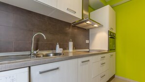 Eine moderne Küche mit Spüle aus Edelstahl, Backofen und einer Wand in Grünton.