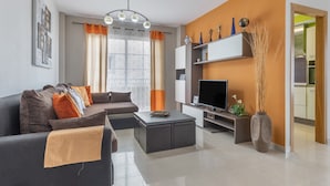 Ein modernes Wohnzimmer mit Sofa, Couchtisch, Fernseher und Dekorationselementen.