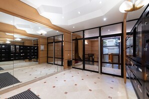 Una moderna hall d'albergo con un divisorio in vetro, una reception e un'area dedicata all'archiviazione con mobili contenitori.