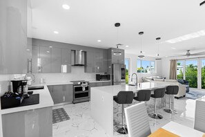 Una cocina moderna con una isla central, electrodomésticos de acero inoxidable y un amplio ventanal con vistas a zonas verdes.