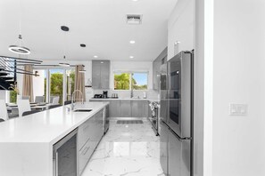 Una cocina moderna con una isla grande, electrodomésticos de acero inoxidable y vistas a zonas verdes.