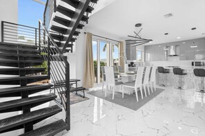 Una cocina moderna con comedor, una escalera y ventanas amplias.