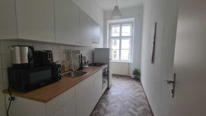 Eine Küche mit weißen Schränken, einer Mikrowelle, einer Kaffeemaschine und einem Herd.