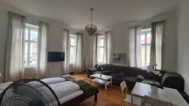 Ein Hotelzimmer mit Bett, Sofa, Esstisch und Fernseher.