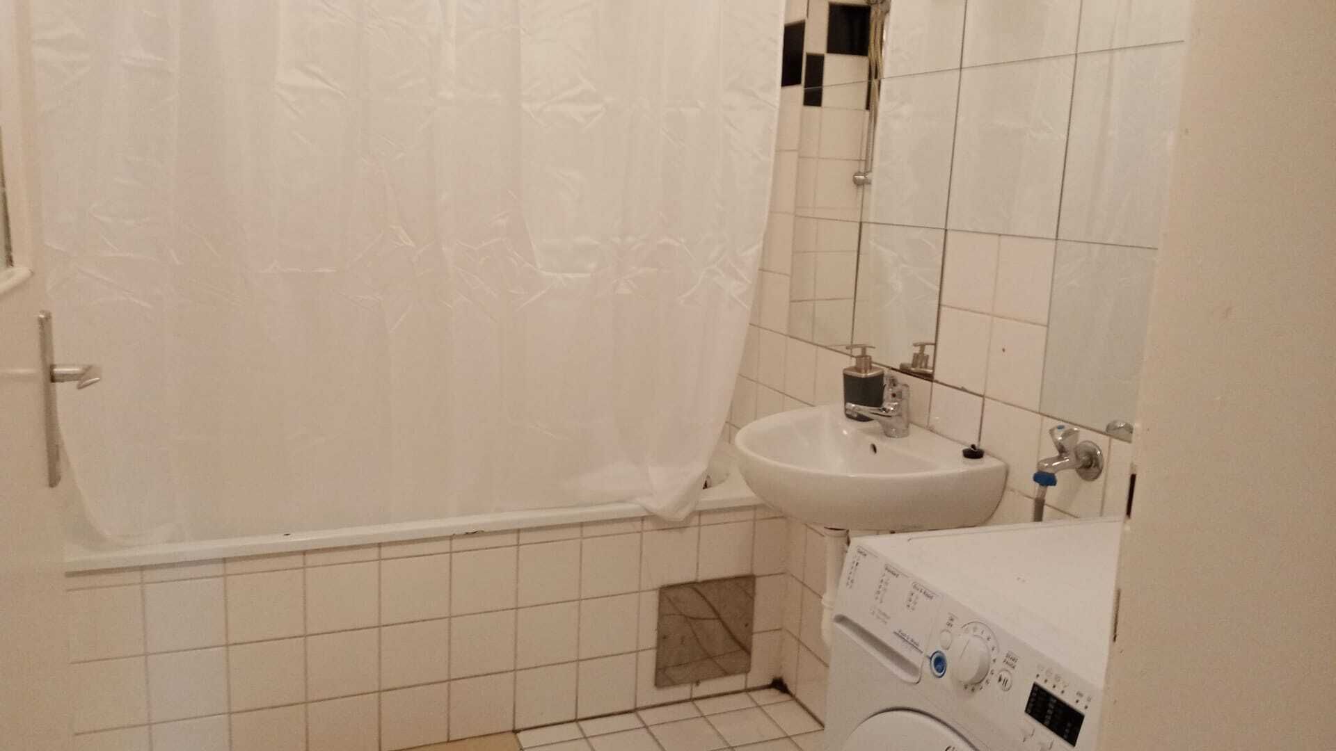A small bathroom with a bathtub, a sink, and a washing machine.