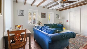 Une pièce avec un plafond en bois, un canapé bleu, une table à manger avec des chaises et un tapis à motifs.