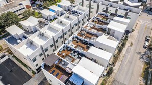 Een modern appartementencomplex met meerdere gebouwen, dakterrassen en een centrale binnenplaats met zitplekken.