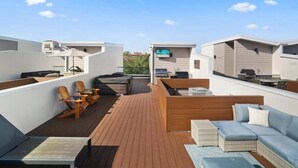 Een dakterras met zitplaatsen, een barbecue en een televisiescherm.