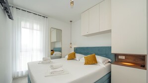 A modern hotel room with a neatly made bed, a large mirror, and a wooden bedside table. - Salt&Stone - apartment with private pool (Novalja)