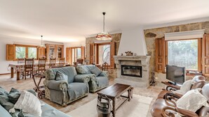 Uma sala de estar ampla com lareira, televisão e área de jantar com móveis de madeira.