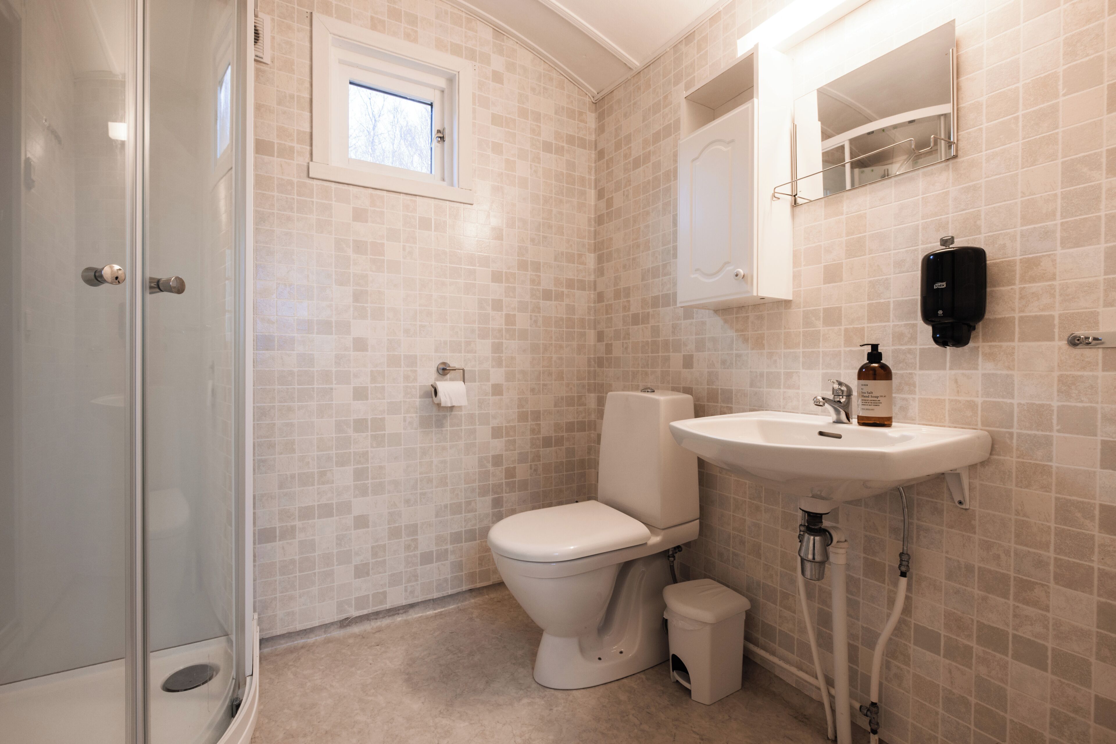 A bathroom with a toilet, sink, and shower.