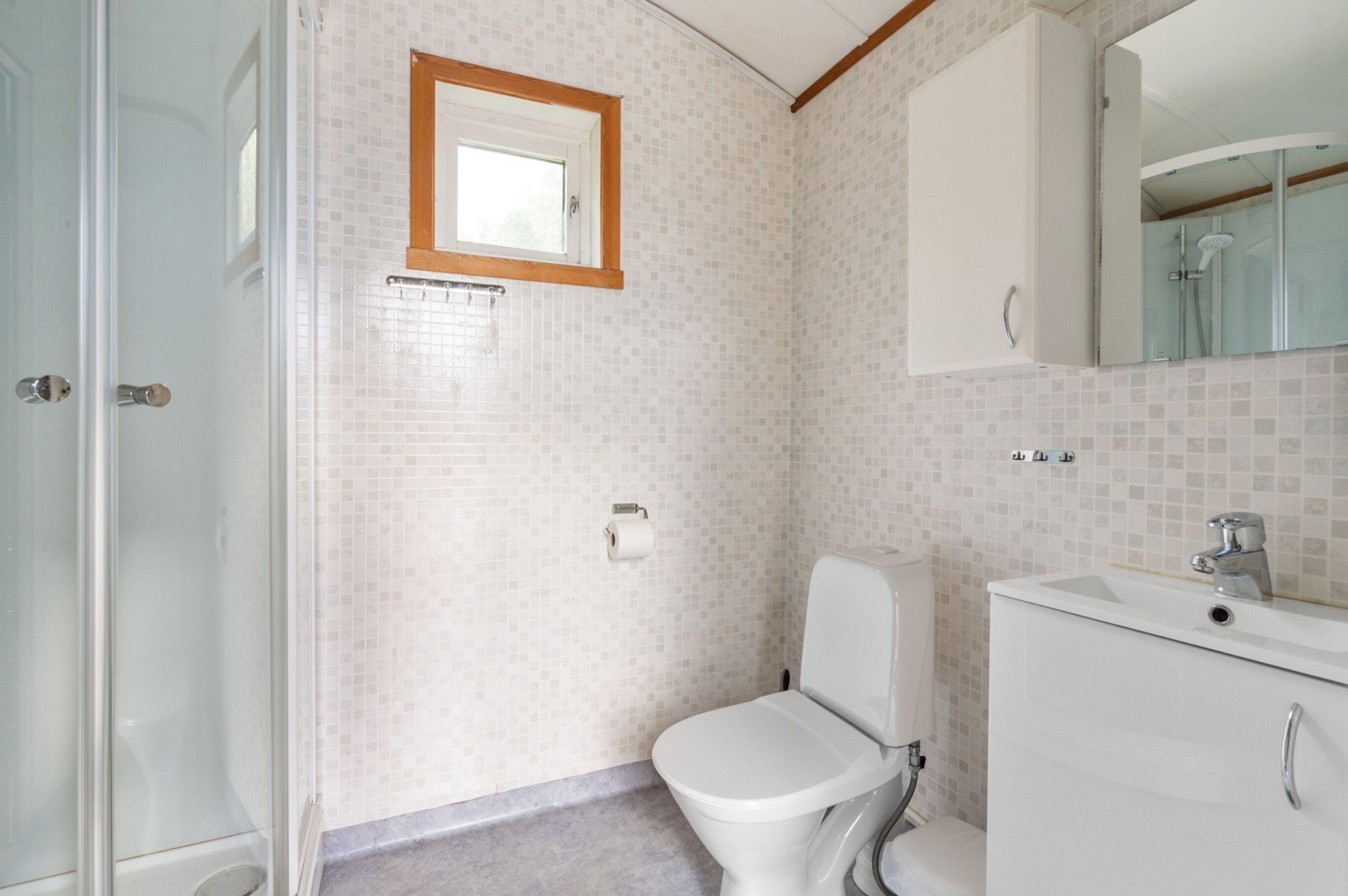 Une salle de bain équipée de toilettes, d’un lavabo, d’un miroir et d’une douche.