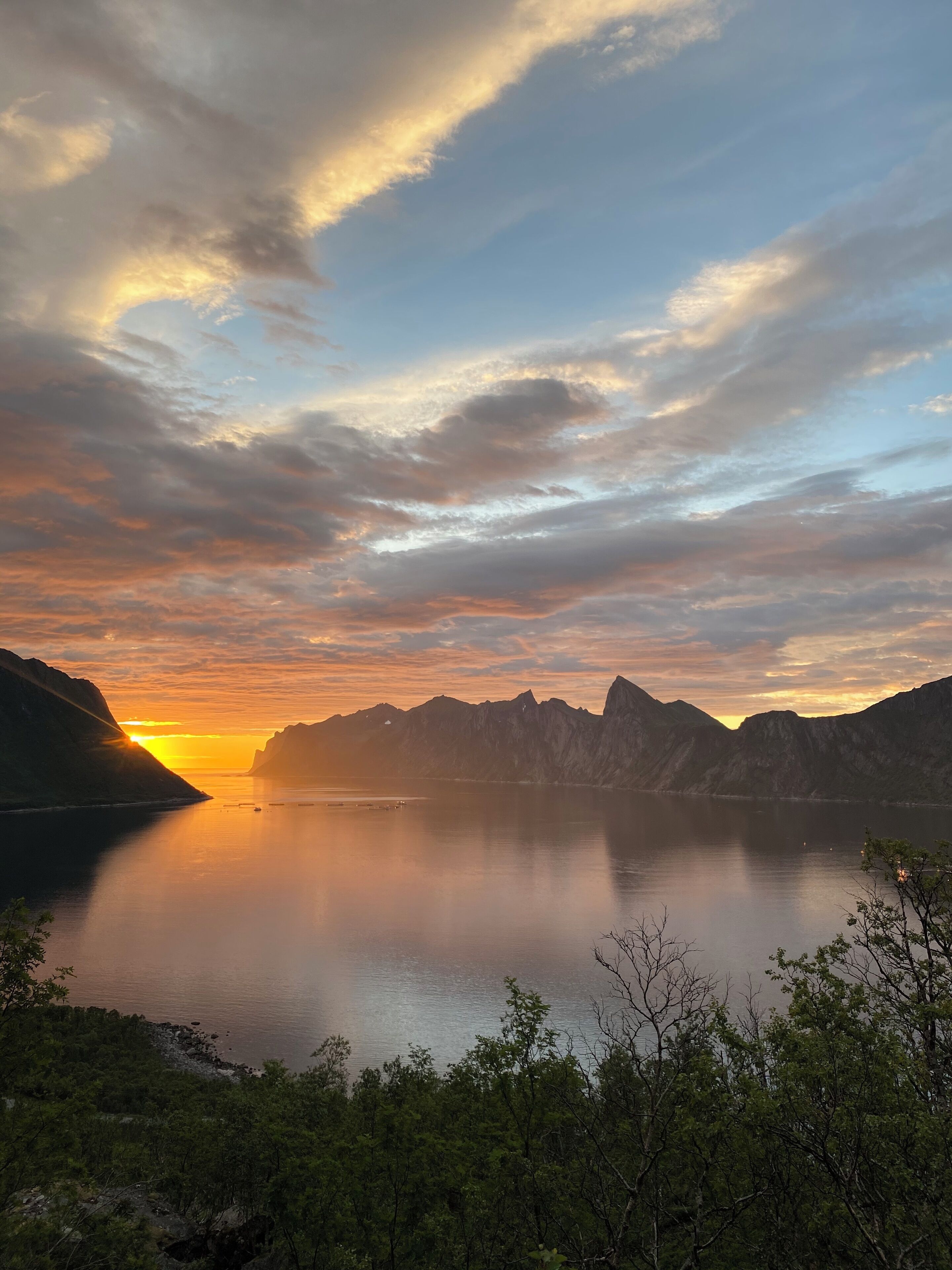 A calm lake at sunset with mountains in the background.