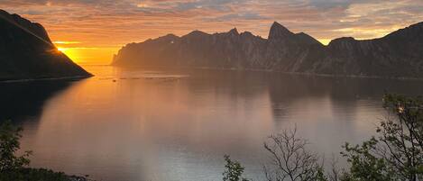 A calm lake at sunset with mountains in the background.
