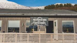 Un bâtiment en bois avec une enseigne indiquant « Nordisk Bris Food & Drinks » et de grandes fenêtres.