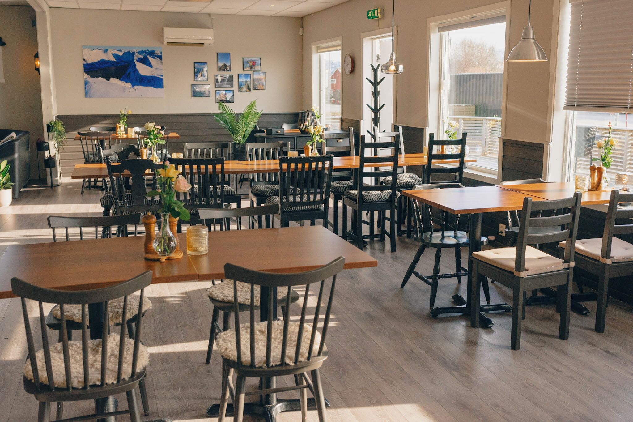 A restaurant with multiple tables and chairs, a large window, and a painting on the wall.