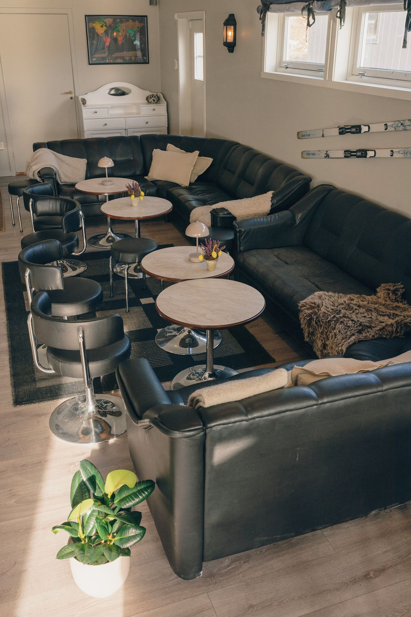 A modern living room with a black leather sofa, round coffee tables, and a white cabinet.