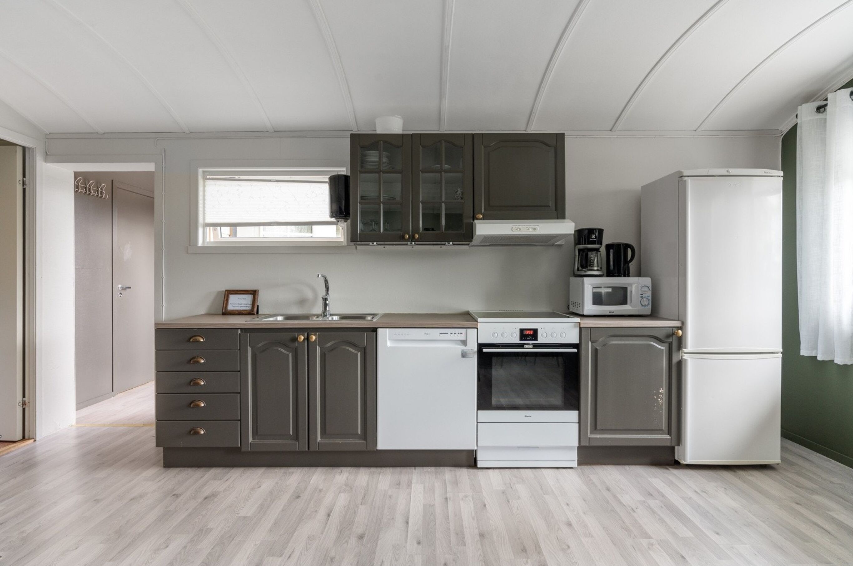 A compact kitchen with a dishwasher, microwave, stove, and refrigerator.