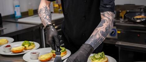 A chef preparing food in a kitchen with stainless steel surfaces and various dishes on plates.