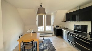 Une cuisine compacte avec un coin repas, comprenant une table en bois, des chaises, un four à micro-ondes et des appareils électroménagers modernes.
