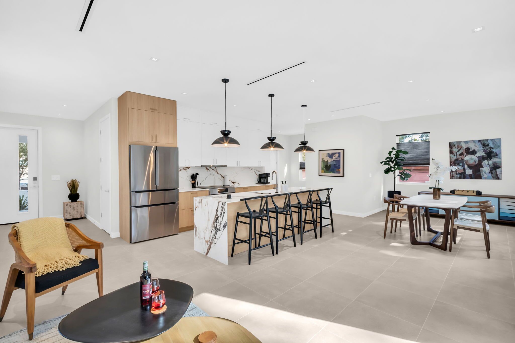 Une cuisine moderne dotée d’un îlot central, de tabourets de bar et de luminaires suspendus.
