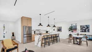 Une cuisine moderne dotée d’un îlot central, de tabourets de bar et de luminaires suspendus.