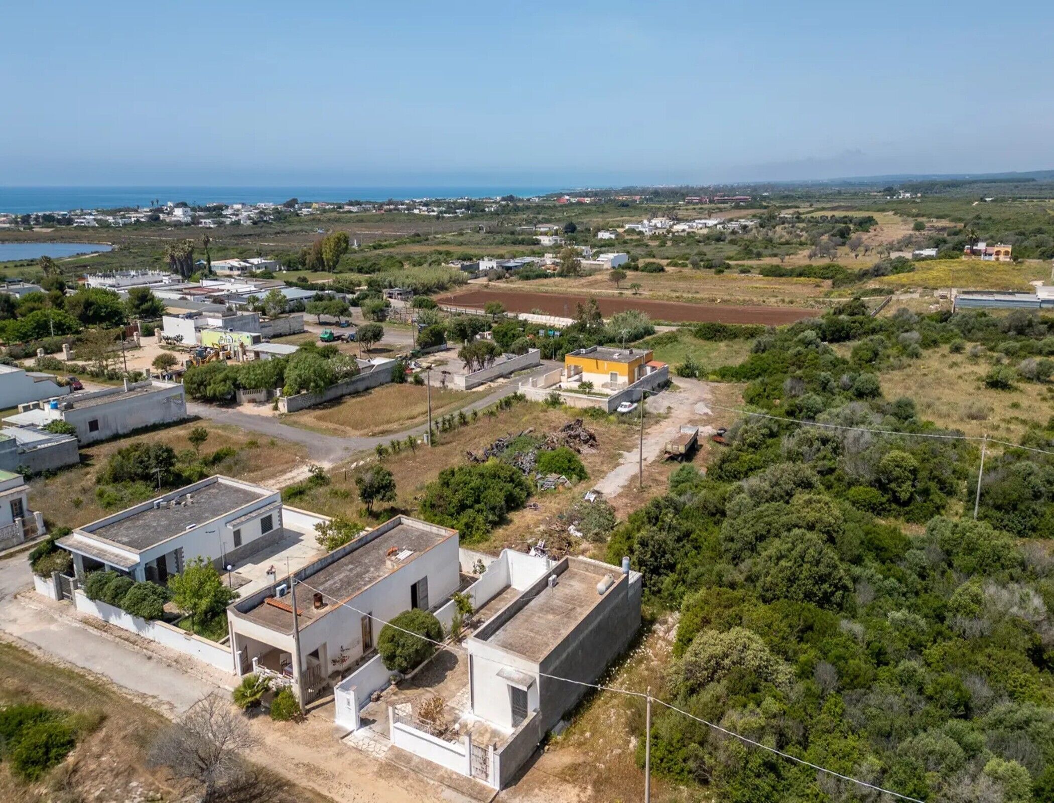 Vue aérienne d’un quartier résidentiel avec des maisons, une route et une étendue d’eau au loin.
