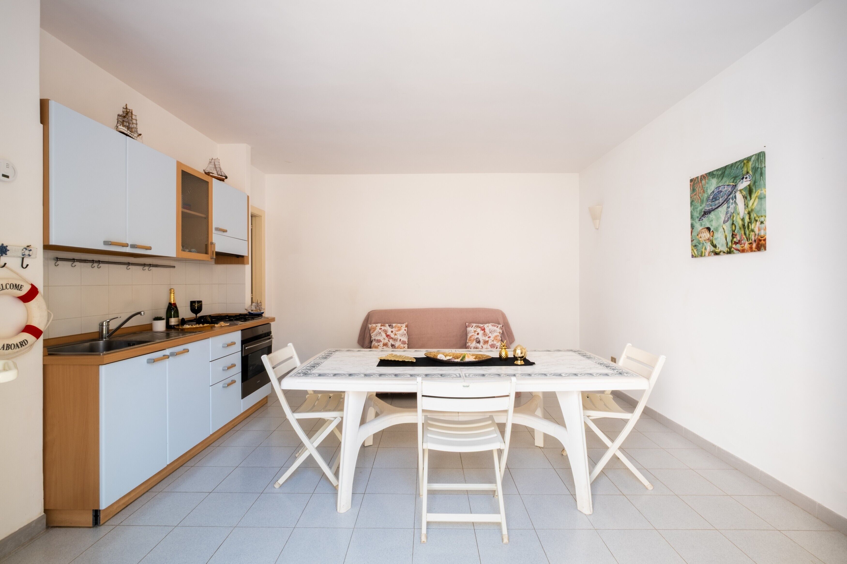 Une cuisine compacte comprenant une table et des chaises, un canapé et un tableau accroché au mur.