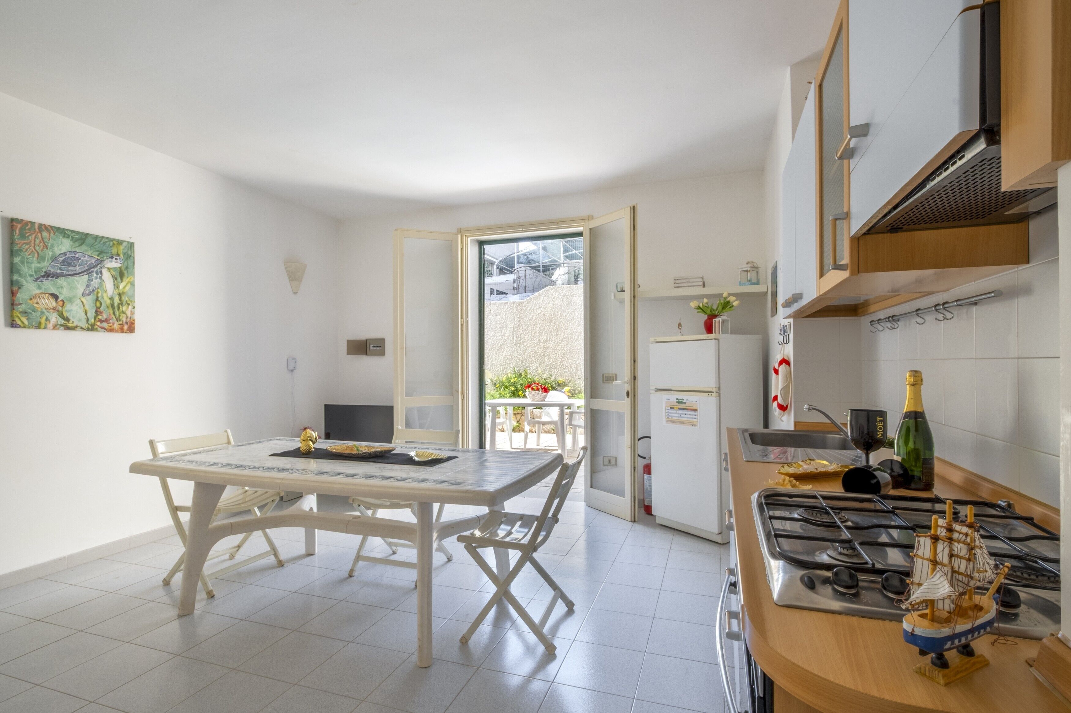 A kitchen with a stove, a small ship model, and a dining area with a table and chairs.