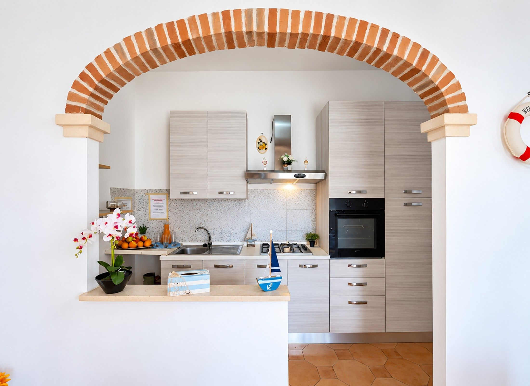 Eine moderne Küche mit einer Ziegelbogenarchitektur, Edelstahlgeräten und einem kleinen dekorativen Segelboot.