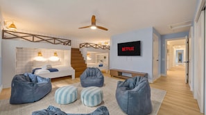 Ein modernes Hotelzimmer mit Bett, Sitzecke, Fernseher und einer Treppe.