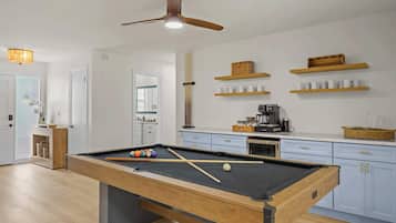 Una cocina moderna con mesa de billar, estantes de madera y ventilador de techo.