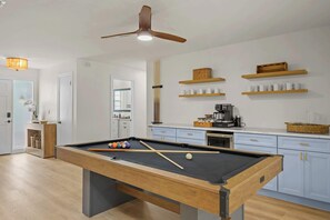 Una cocina moderna con mesa de billar, estantes de madera y ventilador de techo.
