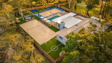 A multi-purpose outdoor area with a basketball court, a pool, and a patio with seating.